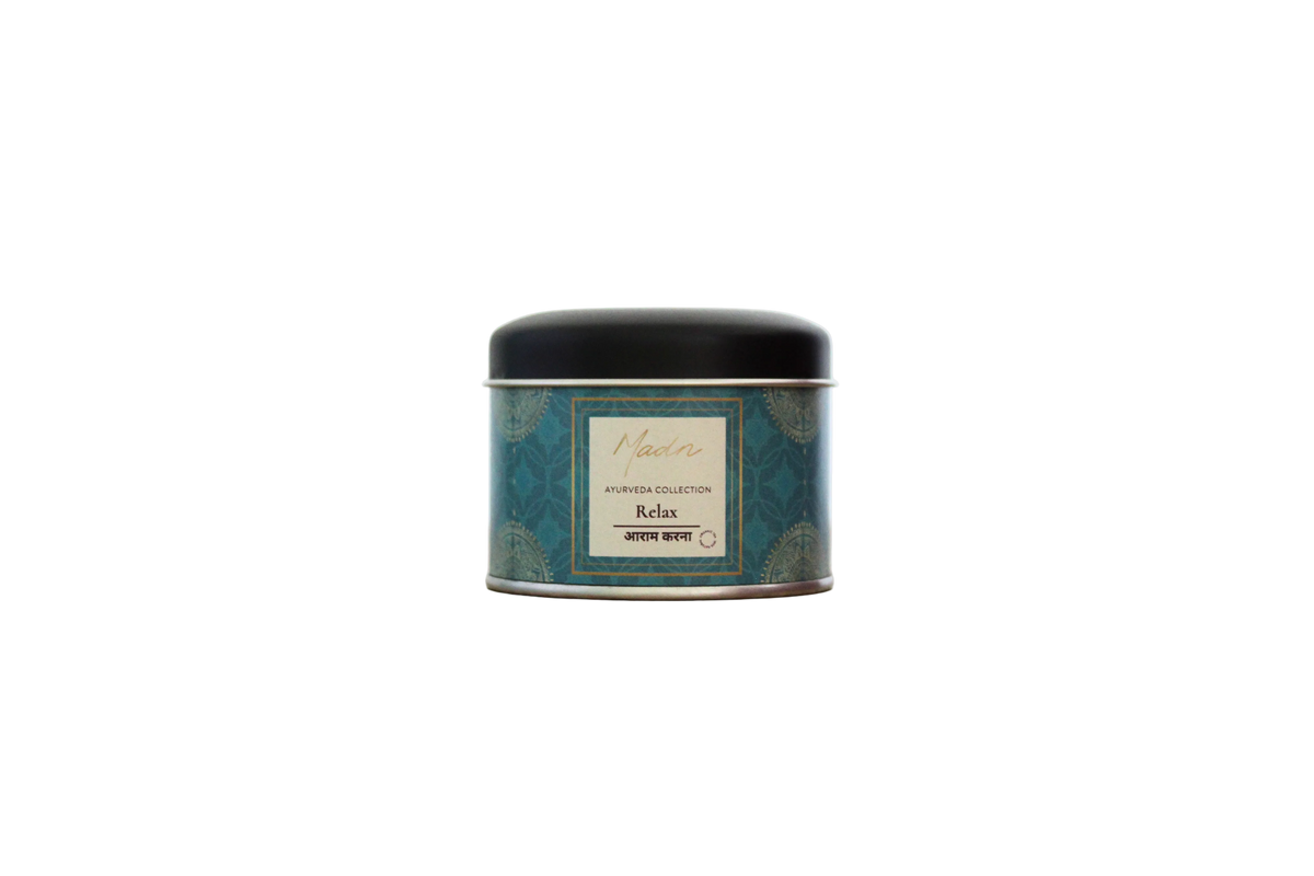 A round metal tin candle with a black lid and a teal patterned label, centered on a plain white background.